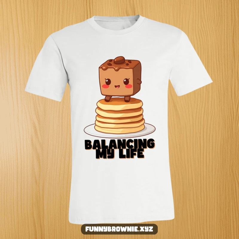Funny t-shirt showing a brownie character grinning while balancing on a wobbly stack of pancakes, embodying playful precariousness.