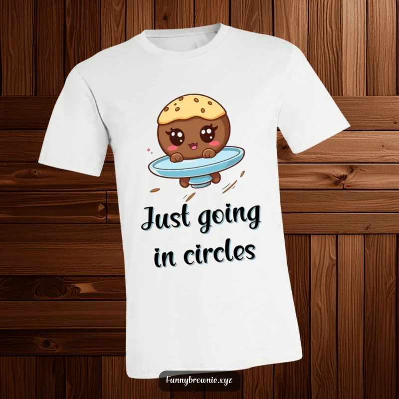 Funny t-shirt showing a round brownie character with googly eyes spinning wildly on a plate, conveying pure, dizzy amusement.